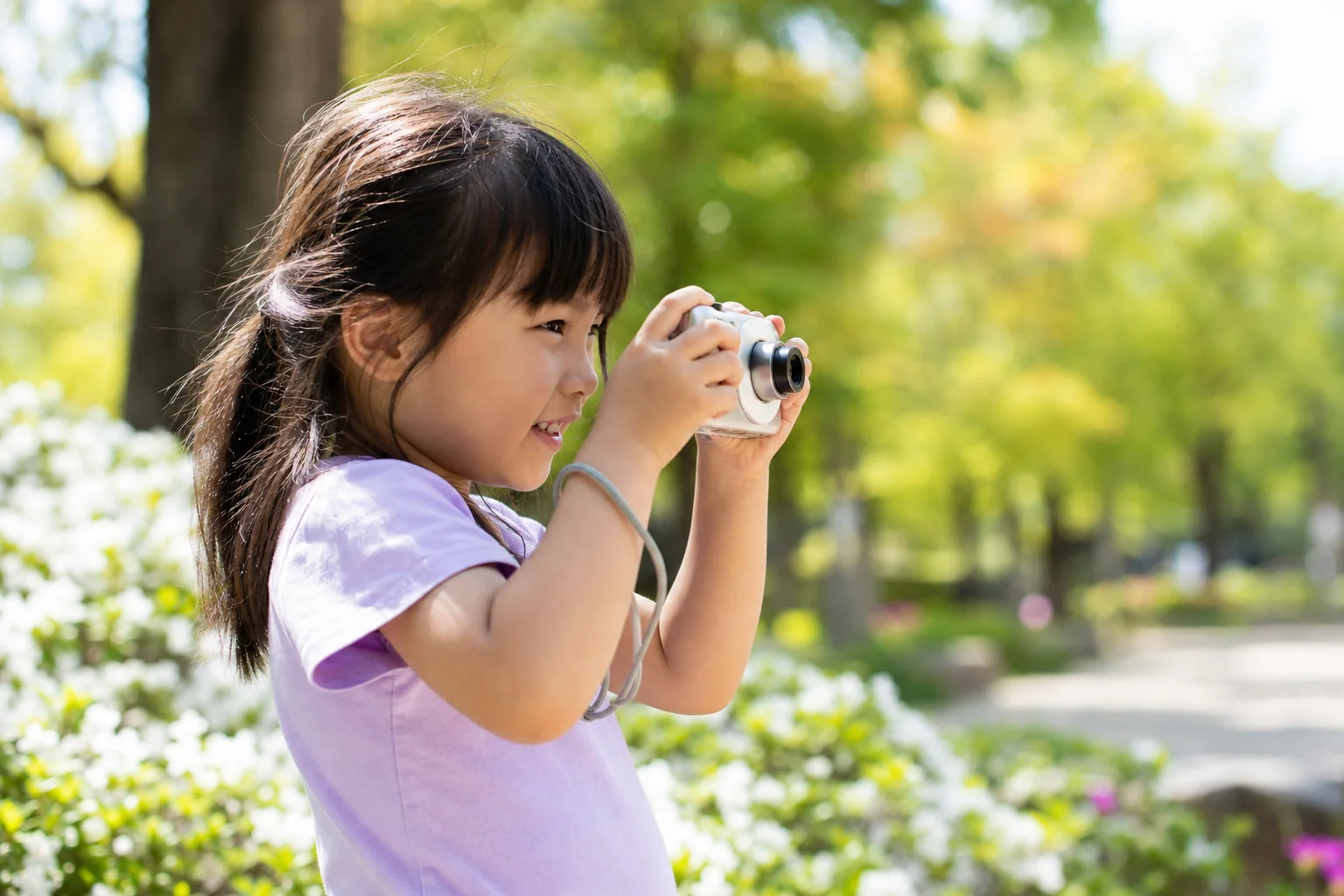 Child taking photos with compact digital camera in a park
